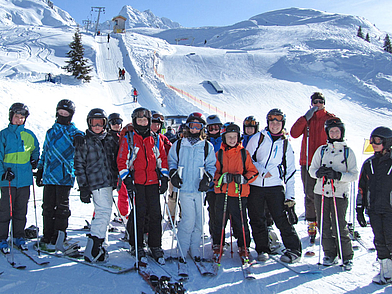 Schülergruppe beim Skifahren in den Alpen