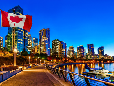 Vancouver di notte con lo skyline illuminato, il lungomare e la bandiera canadese