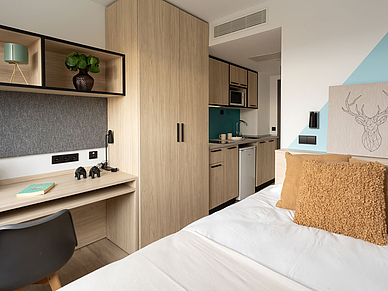 Modern eingerichtetes Einzelzimmer der Residenz in Salamanca mit Bett, Schreibtisch und Küchenzeile für Sprachschüler.