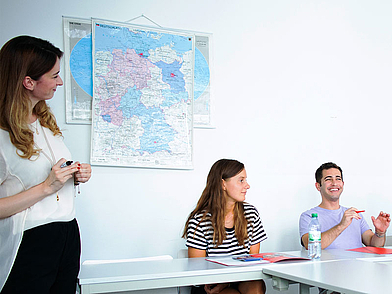 Lehrkraft erklärt Inhalte an einer Karte im Deutschunterricht