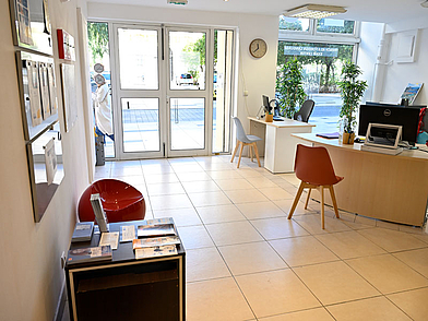 Area della reception della scuola di lingue Les Ateliers FL di Nizza con il banco di consulenza e la porta d'ingresso.