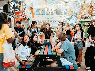 Jugendliche an einem bunten Tisch in einer belebten Markthalle, während ihrer Englisch Sprachreise nach Oxford.