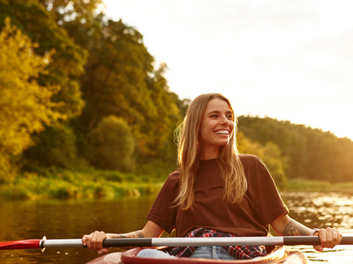 Una giovane donna in kayak su un fiume tranquillo al tramonto, immersa nella natura