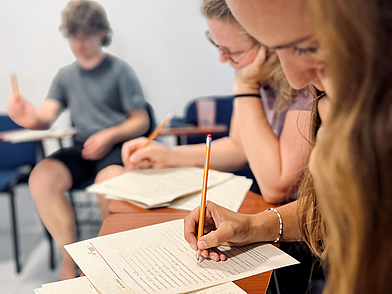 Concentration lors de l'apprentissage de l'espagnol à Carthagène, gros plan sur des étudiants en cours avec des outils de travail typiques.