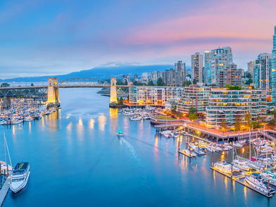 Skyline di Vancouver sul lungomare con ponte, porto turistico e luci della città al crepuscolo