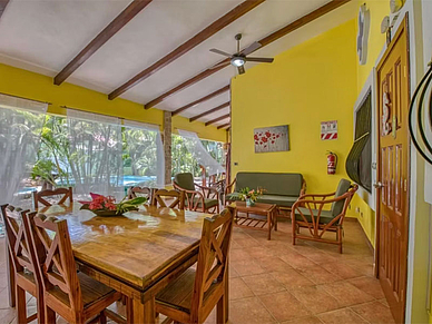 Lounge-Sitzbereich der Villas Verdes Sámara mit großem Holzesstisch und Blick auf den tropischen Garten.