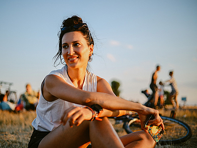 Junge Frau sitzt entspannt im Sonnenuntergang auf dem Tempelhofer Feld in Berlin – Deutschkurs Berlin Young Adults