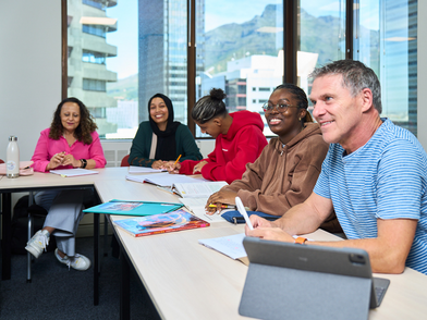 Sprachschüler lernen gemeinsam im hellen Klassenzimmer mit Blick auf Kapstadt