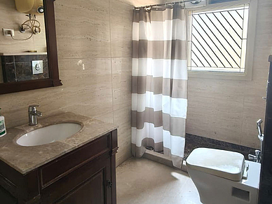 Badezimmer im Apartment in Neu-Delhi mit Dusche, Waschbecken und Fenster.