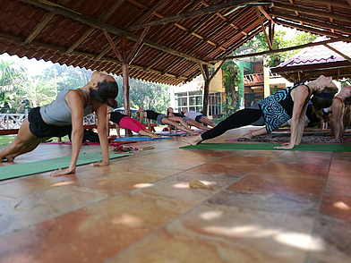 Yogastunde im Freien auf dem Gelände der Intercultura Sprachschule Sámara mit traditionellen Pavillons.
