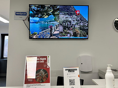 Empfangstresen der Sprachschule StL WeSpeak Lugano mit Bildschirm und Kursinfos
