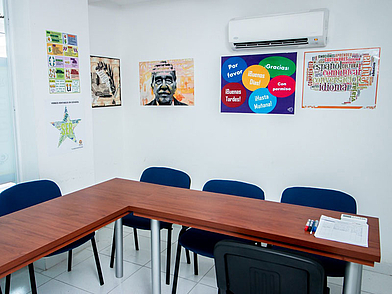 Salle de classe moderne de l'école de langue ECOS Cartagena avec des affiches murales colorées et un équipement simple, idéal pour les cours d'espagnol en petits groupes.