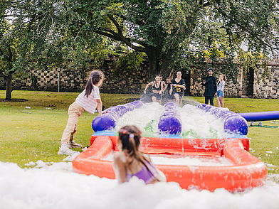 Jugendliche nehmen an einer spaßigen Outdoor-Aktivität mit Rutschbahn und Schaum teil, ein Highlight des Freizeitprogramms der Sprachreise nach Canterbury.
