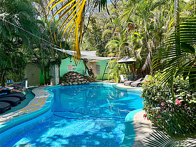 Tropischer Pool der Villas Verdes in Sámara, umgeben von Palmen, Liegestühlen und schattigen Ruhebereichen.