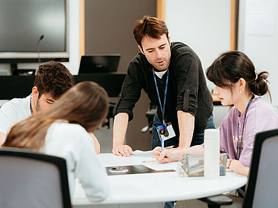Lehrkraft unterstützt die Jugendlichen gezielt bei einer Schreibübung.