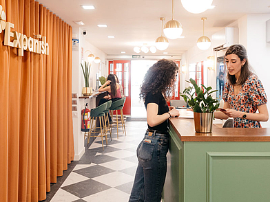 Moderna reception della scuola di lingue Expanish di Madrid, dove un membro del personale dà il benvenuto a un nuovo studente di lingue.