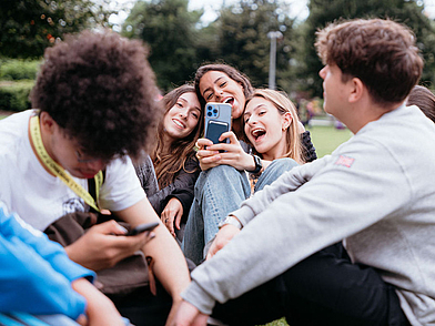 Freizeitmoment im Park – Schüler sitzen zusammen und lachen gemeinsam.