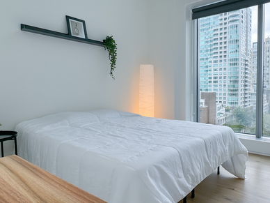 Confortevole camera da letto dell'alloggio CEL Vancouver con letto matrimoniale e vista sulla città