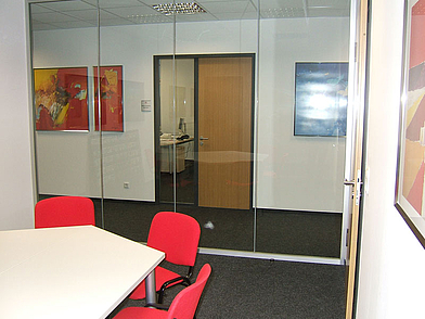 Besprechungsraum mit Glaswänden und roten Stühlen in der Sprachschule Hamburg
