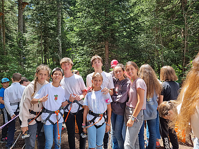 Jugendliche Teilnehmer einer Schüler-Sprachreise in Liddes beim Kletterpark-Abenteuer im Wald.