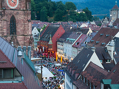 Blick über den vollen Münsterplatz in Freiburg beim Stadtfest, Sprachreise-Teilnehmer erleben Kultur und Geselligkeit.