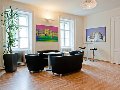 Aufenthaltsraum der ActiLingua Sprachschule Wien mit Sitzgelegenheiten und modernen Bildern.