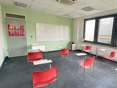 Helles Klassenzimmer der Sprachschule in Frankfurt mit Whiteboard und roten Stühlen