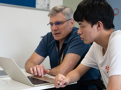 Englischlehrer der Sprachschule Oxford unterstützt einen Schüler beim Lernen am Laptop.