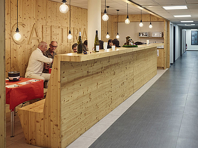 Moderne Cafeteria der Sprachschule Ifalpes in Annecy mit Holzdesign, die als Treffpunkt für Sprachschüler dient und Raum für Pausen und Austausch bietet.