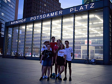 Gruppe junger Menschen steht abends vor dem Bahnhof Potsdamer Platz in Berlin