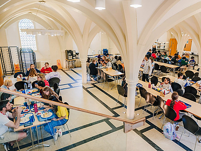 Schüler essen gemeinsam in der historischen Schulkantine mit gotischen Bögen – ein typischer Mittag während des Sprachaufenthalts in England.