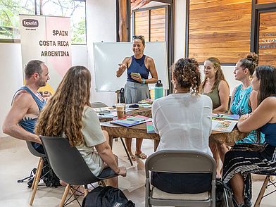 Lehrerin unterrichtet eine kleine Gruppe Erwachsener in der Expanish Sámara Sprachschule in einem hellen, offenen Klassenraum.