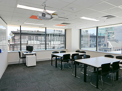 Helles, modernes Klassenzimmer der ILSC Adelaide mit großen Fenstern, Beamer und Gruppentischen – ideal für interaktiven Englischunterricht in kleinen Lerngruppen.