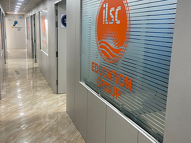 Heller Flur der ILSC Sprachschule in Neu-Delhi mit Glastüren und orangefarbenem Logo der ILSC Education Group.