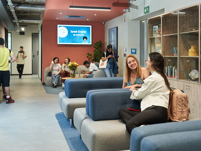 Aufenthaltsbereich der Sprachschule mit Sofas und Studierenden in entspannter Atmosphäre