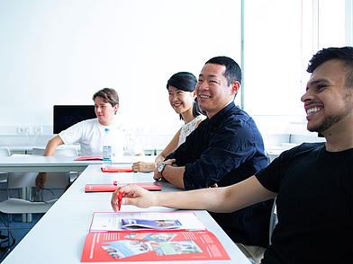 Gruppe internationaler Teilnehmender lächelt im Deutschkurs