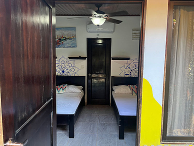 Zimmer in der Studentenresidenz in Sámara mit zwei Betten, Klimaanlage und direktem Zugang.