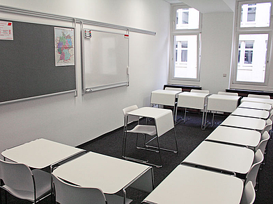 Heller Unterrichtsraum mit modernen weißen Tischen und Stühlen für Sprachkurse in Hamburg