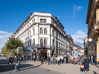 Das Schulgebäude in der historischen Altstadt Heidelberg mit belebter Fußgängerzone