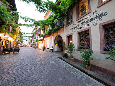 Kopfsteinpflasterstraße in Freiburg mit historischen Fassaden und Weinstube – idealer Ausgangspunkt für eine Sprachreise in den Schwarzwald.