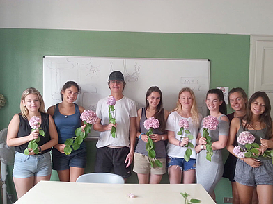 Gruppe von Sprachschülern im Klassenraum mit Blumen – gemeinsames Lernen in Viareggio